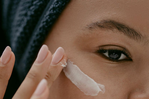A woman applying eye cream.