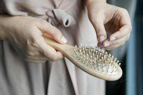A woman removing hair from a hairbrush.