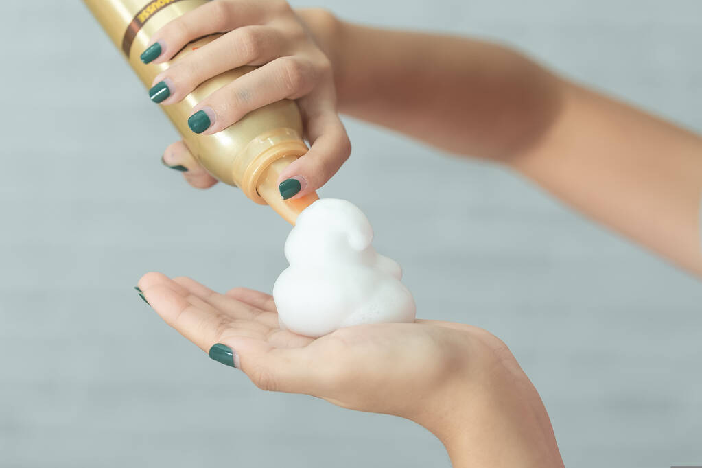 A woman’s hand with hair mousse spray.